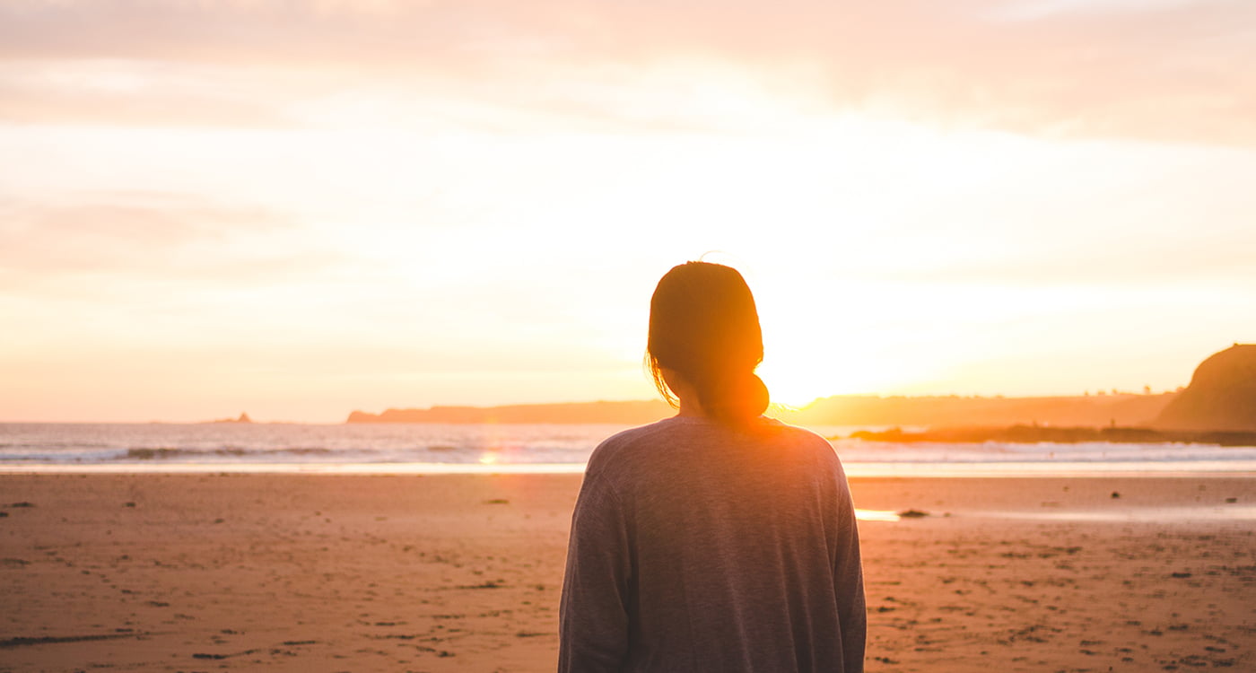 woman on the beach staring into the sunset